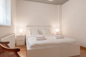 a white bedroom with a bed and a chair at Aristocratic Home Under Acropolis in Athens