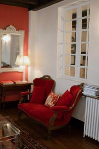 uma cadeira vermelha sentada num quarto com uma janela em Grand Hôtel de la Poste em Saint-Jean-de-Luz