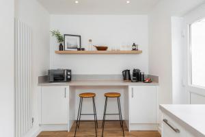 a kitchen with two stools and a counter with a microwave at Crescent Apartments in Newport