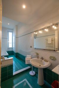 zieloną i białą łazienkę z umywalką i lustrem. w obiekcie ROMAMOREMIO w Rzymie