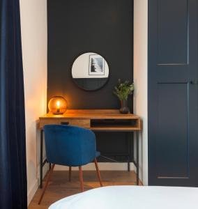 Crescent Apartments في نيوبورت: غرفة نوم مع مكتب مع مرآة وكرسي أزرق