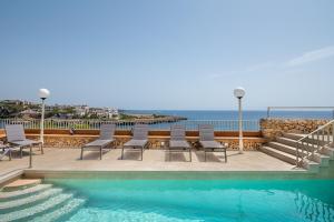 una piscina con sillas y vistas al océano en Villa Enderrossall en Porto Cristo