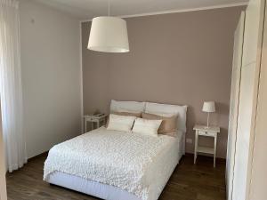 - une chambre dotée d'un lit blanc avec des oreillers et une lampe dans l'établissement Appartamento La Terrazza, à Trieste