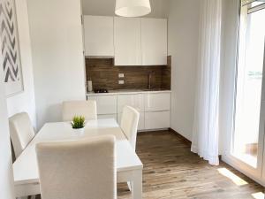 Il dispose d'une cuisine et d'une table à manger blanche avec des chaises. dans l'établissement Appartamento La Terrazza, à Trieste