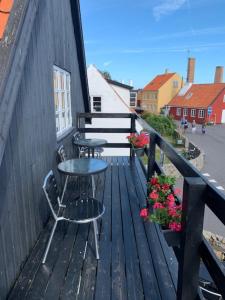 una terraza de madera con 2 sillas, una mesa y flores en Gudhjem Vandrerhjem / Gudhjem Hostel, en Gudhjem
