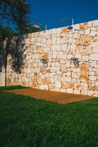 a stone wall with a basketball court in the grass at Olea Relais in Conversano
