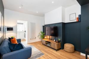 a living room with a blue couch and a tv at Crescent Apartments in Newport