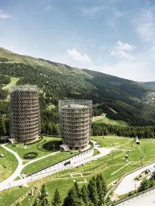 dos torres en un campo con montañas en el fondo en Falkensteiner Residences edelweiss en Katschberghöhe