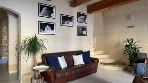 a living room with a brown couch and pictures on the wall at Fiftyfour West Boutique Living in Għarb