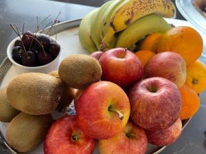 a bowl of apples oranges and other fruits on a table at Fiftyfour West Boutique Living in Għarb