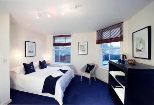 a bedroom with a bed and a desk and two windows at The Royal Burnham Yacht Club in Burnham-on-Crouch