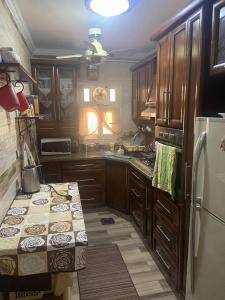 cocina con armarios de madera y nevera en nora's apartment, en El Cairo