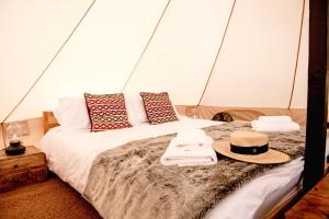a bed in a tent with a hat on it at Oastbrook Glamping in Bodiam