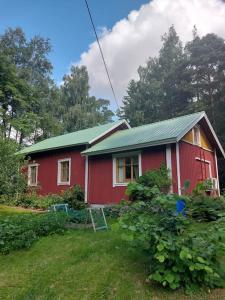 una casa roja con un techo verde en un patio en Idyllinen mökki Laitilassa, en Laitila