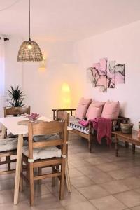 comedor con mesa y bancos con almohadas rosas en Apartamentos Can Salas, en Cala Figuera