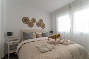 Un dormitorio blanco con una cama con toallas. en Cala Luxo en Cala de Mijas a metros del mar en Mijas Costa