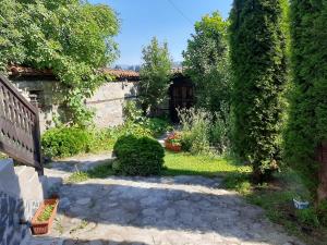 a garden with a stone wall and a tree at Guest House Edelweiss in Koprivshtitsa