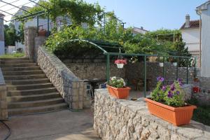 a garden with flowers in pots on a stone wall at Double Room Njivice 5458a in Njivice