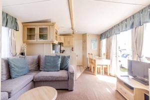 a living room with a couch and a table and a kitchen at By The Seaside Dog Friendly Caravan At Haven Hopton In Norfolk Ref 80015w in Great Yarmouth