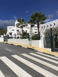 uma rua vazia com um edifício branco e palmeiras em Luxury apartment in Golf Hills, Estepona. em Estepona