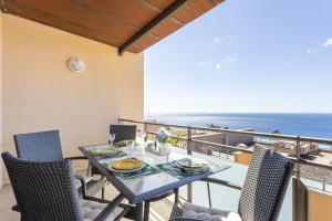 Chalet con vistas al mar en Santa Cruz de Tenerife في سانتا كروث دي تينيريفه: طاولة طعام وكراسي على شرفة مع المحيط