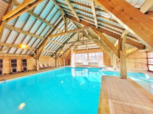 une grande piscine intérieure avec un grand plafond dans l'établissement Madame Vacances Residence Les Fermes de Saint Sorlin, à Saint-Sorlin-dʼArves