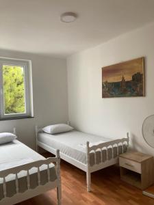 a bedroom with two beds and a painting on the wall at Apartman Jelena in Mostar