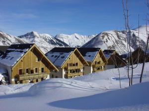 a group of houses in the snow with mountains at Madame Vacances Residence Les Fermes de Saint Sorlin in Saint-Sorlin-dʼArves