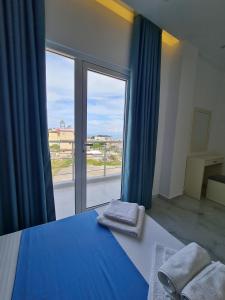 a bedroom with a blue bed and a large window at Apartments Mario in Ksamil