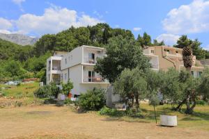 a building in the middle of a field with trees at Apartments with a parking space Tucepi, Makarska - 2676 in Tučepi
