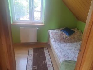 um pequeno quarto verde com uma cama e uma janela em Domek u Ani em Orelec