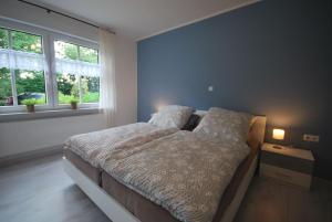 a bedroom with a bed and two windows at Ferienwohnung Up Hobarg 35523 in Uplengen