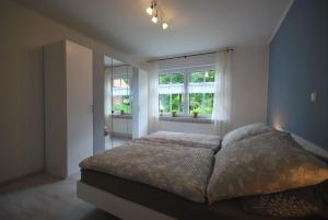 a bedroom with a large bed and two windows at Ferienwohnung Up Hobarg 35523 in Uplengen