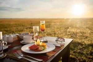 una mesa con un plato de comida y una copa de vino en Cherero Camp en Serengeti