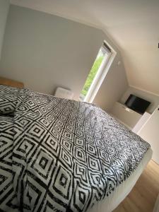 Schlafzimmer mit einem schwarzen und weißen Bett und einem Fenster in der Unterkunft Cute house in Kretowiny