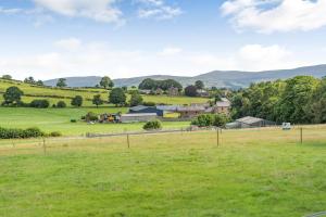 Blick auf einen Bauernhof mit einem Feld und Bergen im Hintergrund in der Unterkunft Ingleborough View in Carnforth