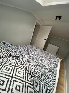 a bedroom with a bed with a black and white comforter at Cute house in Kretowiny