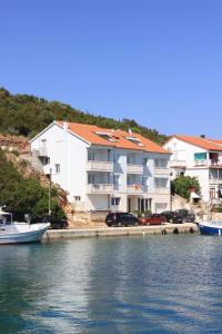 um grande edifício branco com carros estacionados junto à água em Apartments and rooms by the sea Zaglav, Dugi otok - 8144 em Sali