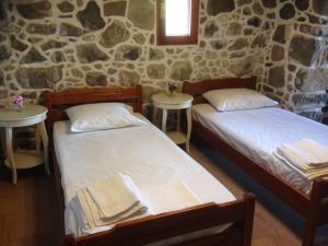 two beds in a room with a stone wall at Loutra Olive Gardens Stone House #1 in Mandrákion