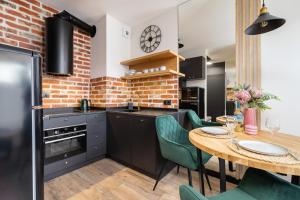 a kitchen with a table and chairs and a brick wall at Solaris Park Apartments Tauron Arena by Renters Prestige in Krakow