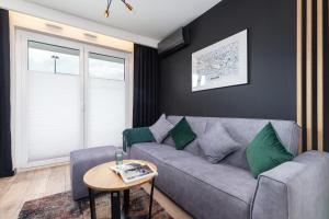 a living room with a gray couch and green pillows at Solaris Park Apartments Tauron Arena by Renters Prestige in Kraków