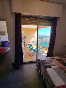 een slaapkamer met een glazen schuifdeur naar een balkon bij appartement vue mer avec parking in Ajaccio