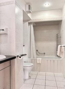 a bathroom with a toilet and a tub and a sink at Beresford Hotel in Dublin