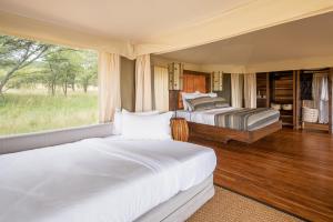 1 Schlafzimmer mit 2 Betten und einem Fenster in der Unterkunft Cherero Camp in Serengeti-Savanne