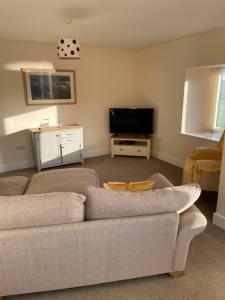 a living room with a couch and a flat screen tv at Glen Cottage 8 Fenton Hill Farm in Wooler