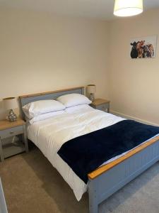 a bedroom with a large bed with two tables at Glen Cottage 8 Fenton Hill Farm in Wooler