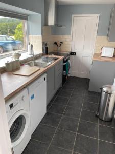 a kitchen with a sink and a washing machine at Tweed Cottage 4 Fenton Hill in Wooler