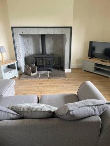 a living room with a couch and a fireplace at Tweed Cottage 4 Fenton Hill in Wooler