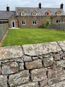 a stone wall in front of a house at Tweed Cottage 4 Fenton Hill in Wooler