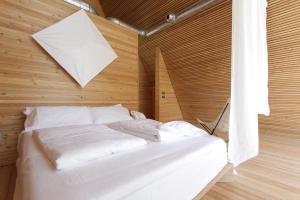 un letto bianco in una camera con pareti in legno di LILELO - Little Leisure Lodge a Grazzano Badoglio